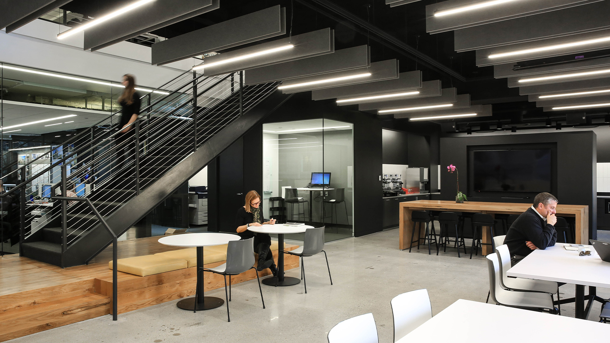 A man and woman sitting at a table in a room with a staircase.