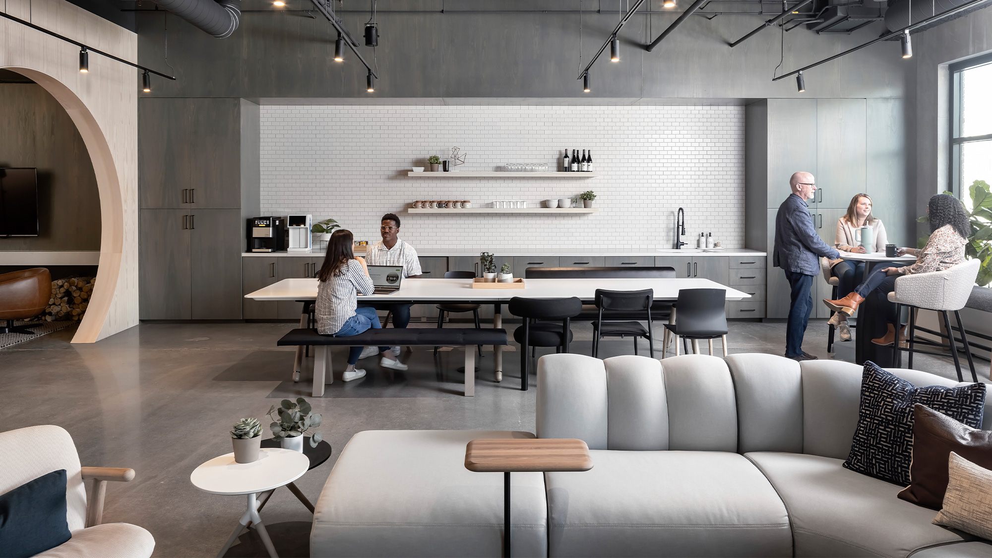 A group of people sitting in a room with a large table and chairs.