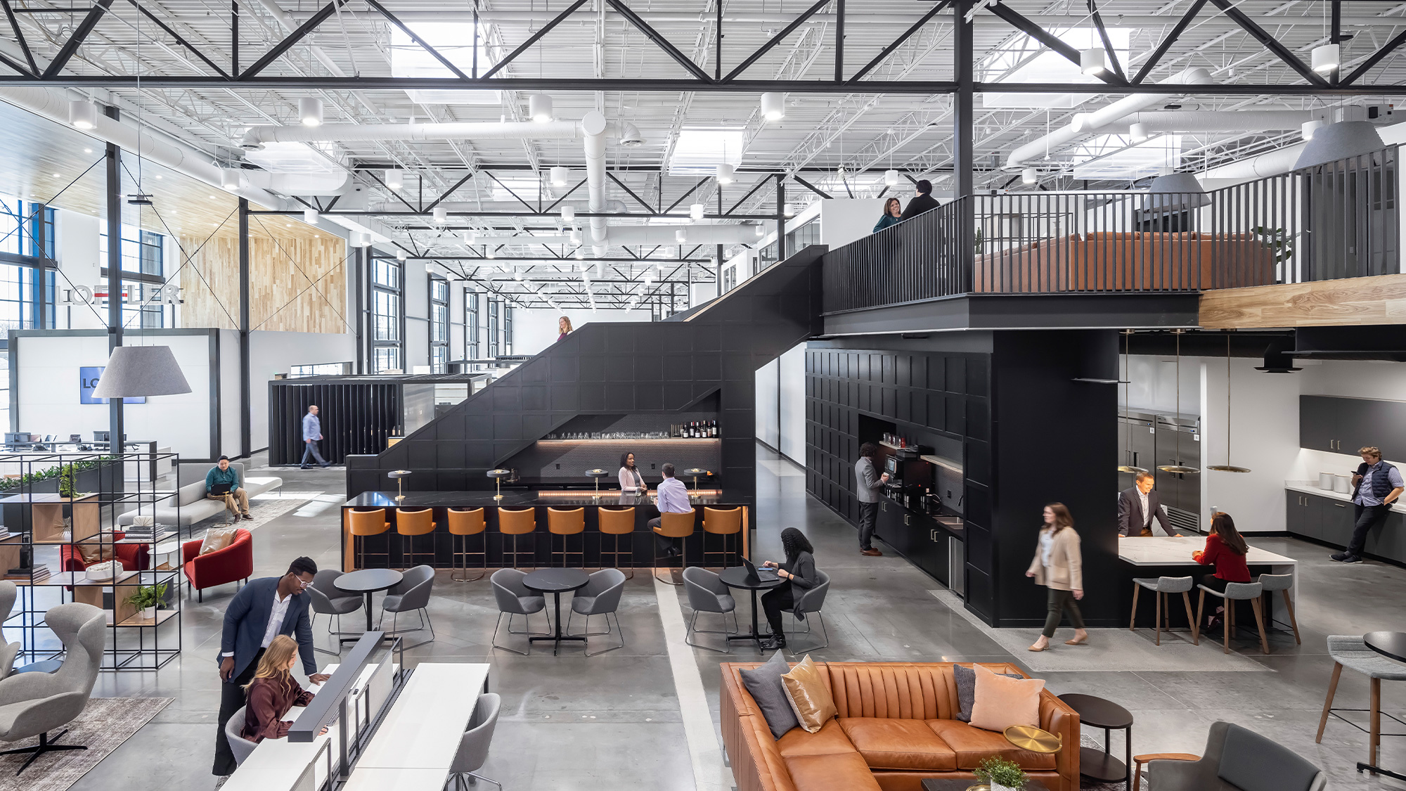 A group of people in a large room with tables and chairs.