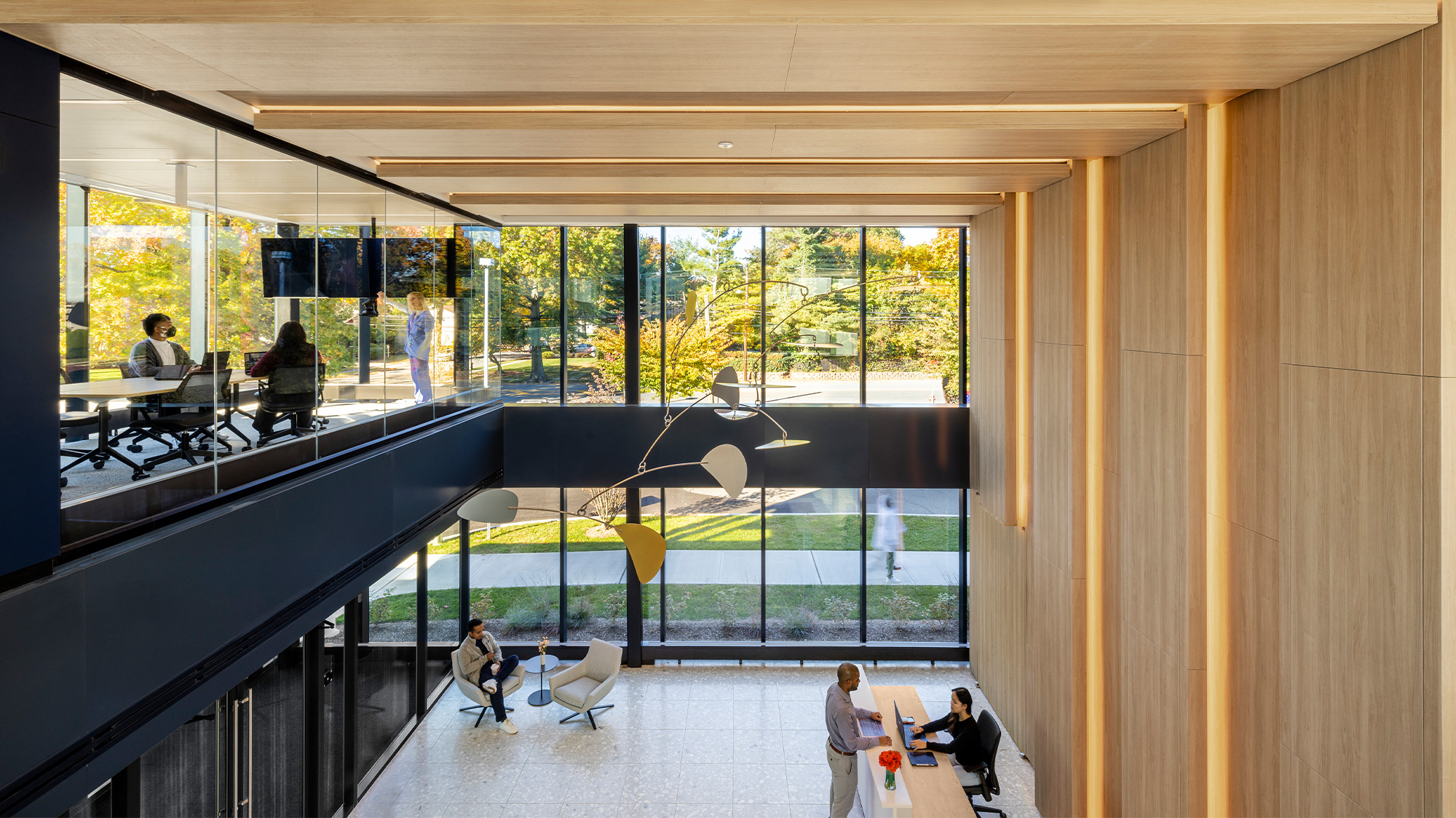A group of people in a room with windows and a large glass wall.