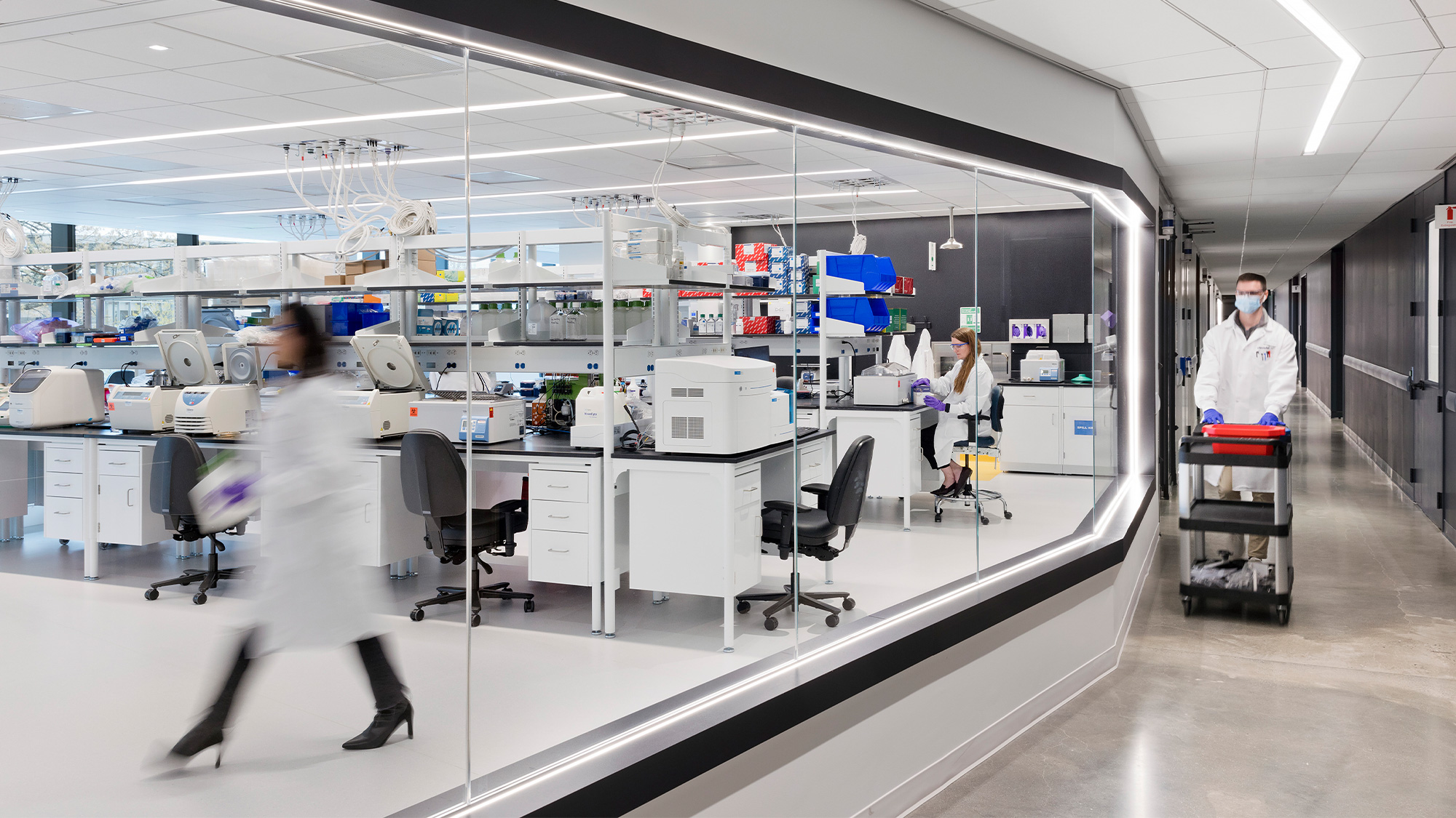 A group of people in white lab coats in a room with computers.