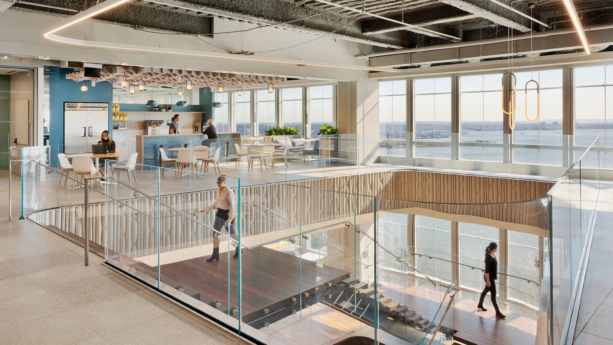 A group of people walking in a large room with windows and tables.